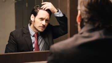 Besorgter Geschäftsmann schaut auf den Haaransatz in den Büroräumen