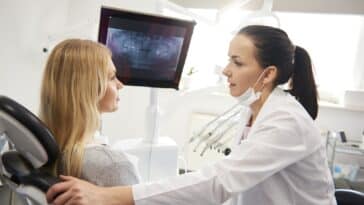 Zahnarzt spricht mit junger Frau während der zahnärztlichen Untersuchung