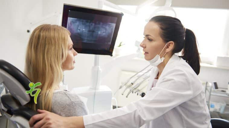 Zahnarzt spricht mit junger Frau während der zahnärztlichen Untersuchung