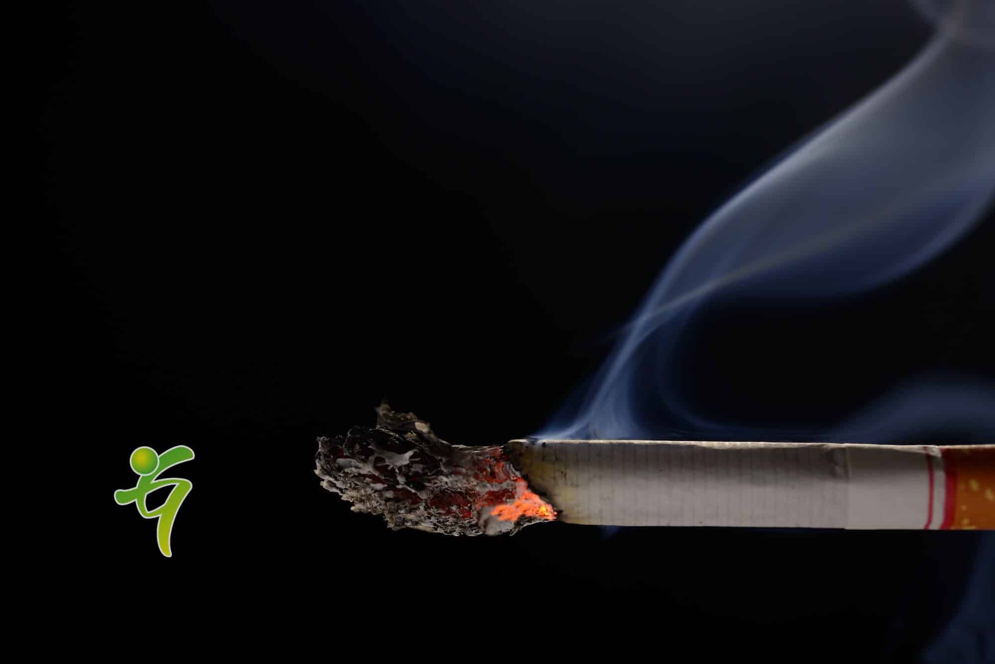Angezündete und brennende Zigarette mit Rauch auf schwarzem Hintergrund