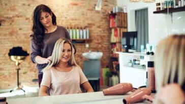 Lächelnde Frau bespricht ihr Haar mit einem Salon-Stylisten