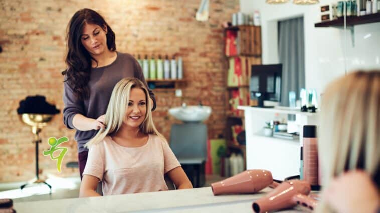 Lächelnde Frau bespricht ihr Haar mit einem Salon-Stylisten