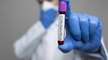 Arzt, der eine Atemmaske trägt und die Coronavirus-Blutprobe hält