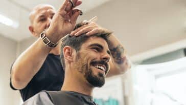 Friseur, der einem attraktiven Mann die Haare schneidet.