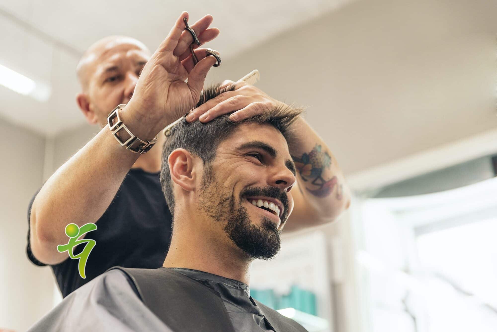 Friseur, der einem attraktiven Mann die Haare schneidet.