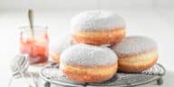 Nahaufnahme von leckeren Donuts mit Puderzucker auf weißem Tisch