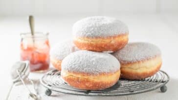 Nahaufnahme von leckeren Donuts mit Puderzucker auf weißem Tisch