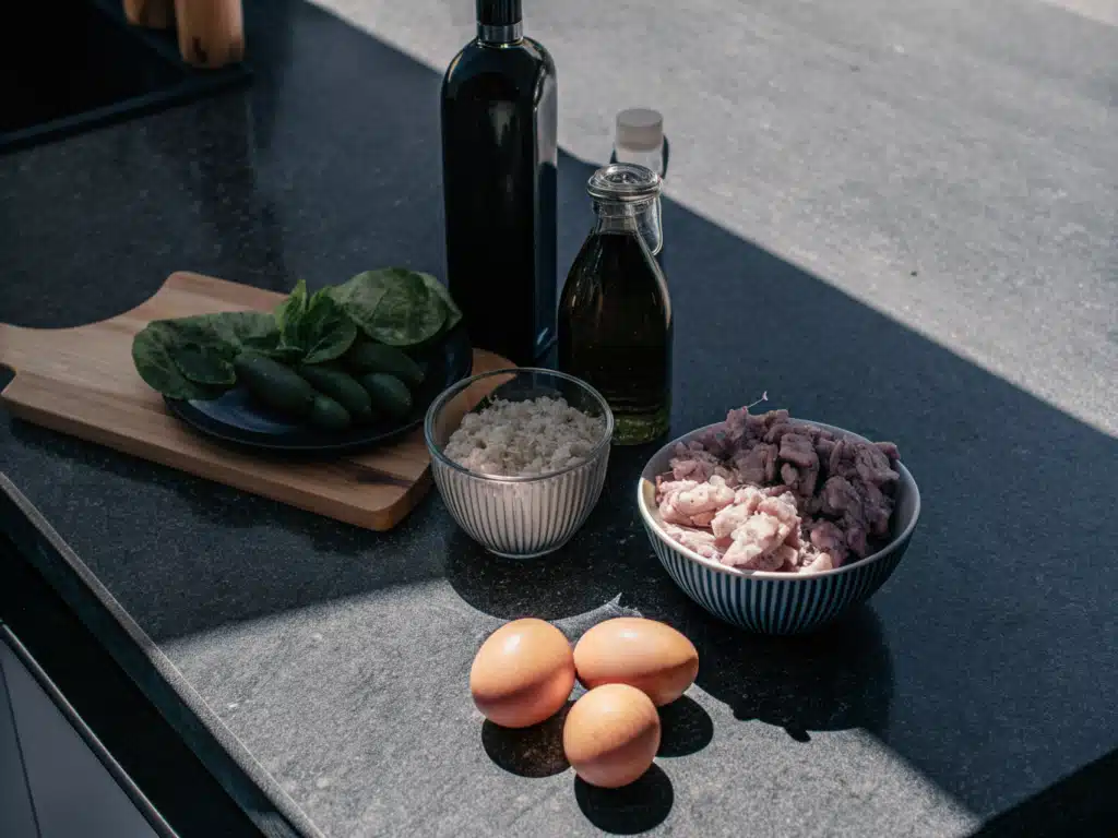 Zutaten für Niçoise-Salat mit Kartoffeln, Eiern, Thunfisch, Spinat und Kapern auf einer Arbeitsfläche